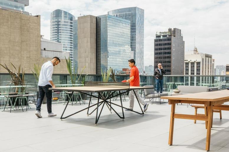 Rooftop terrace at Varsovia 36 Col, Mexico City featuring people playing ping pong with city skyline views.