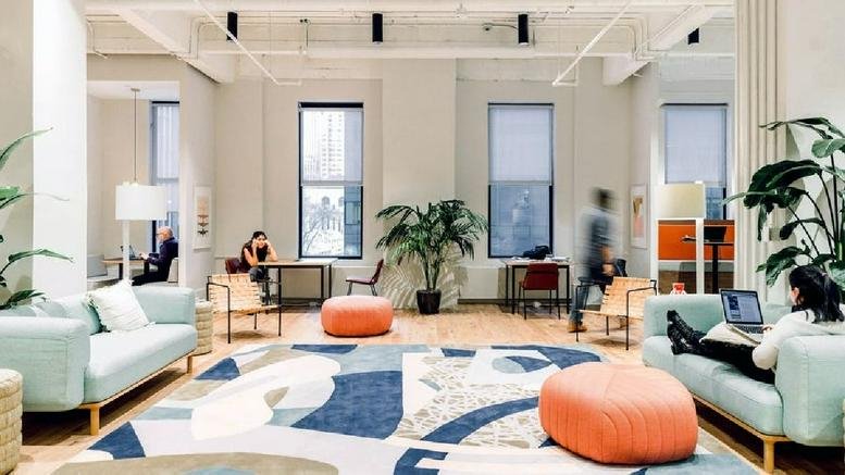 Spacious communal lounge at 130 West 42nd Street with mint green sofas and colorful abstract rugs.