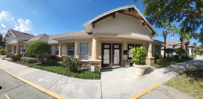 Sunny exterior view of the single-story West Point Plaza building with arched entrance and palm trees.
