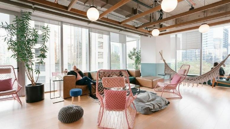 Bright breakout lounge at 165 R. Prof. Atílio Innocenti with pink chairs, hammocks, and floor-to-ceiling windows.