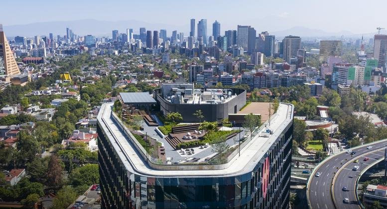 Aerial view of the modern Distrito Polanco building featuring a lush rooftop garden and city skyline.