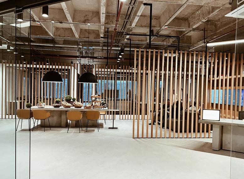 Spacious communal lounge featuring wooden slat partitions and a central dining table.