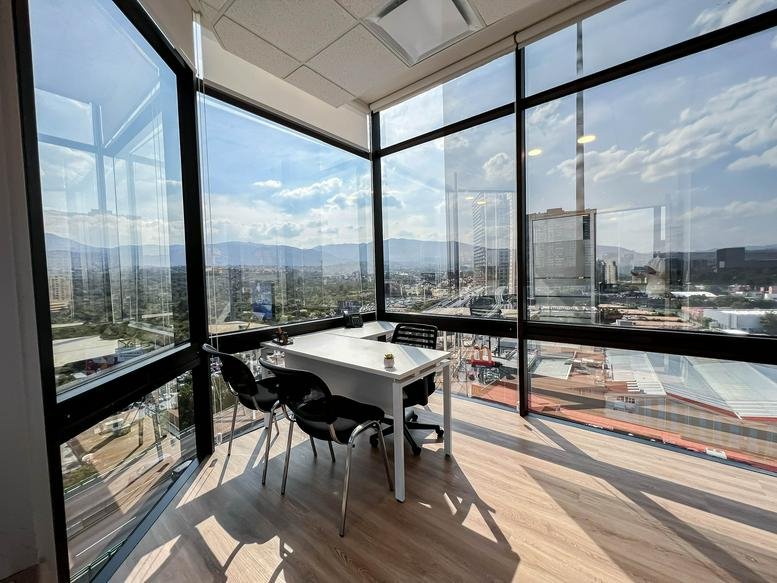 Corner office at Periferico Sur 4118 with floor-to-ceiling windows and panoramic views.
