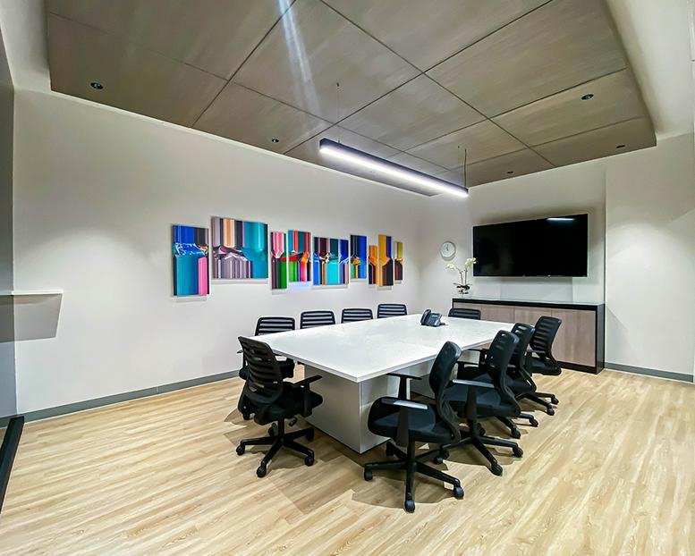 Spacious sunlit breakroom with patterned floor tiles and modern kitchen area.