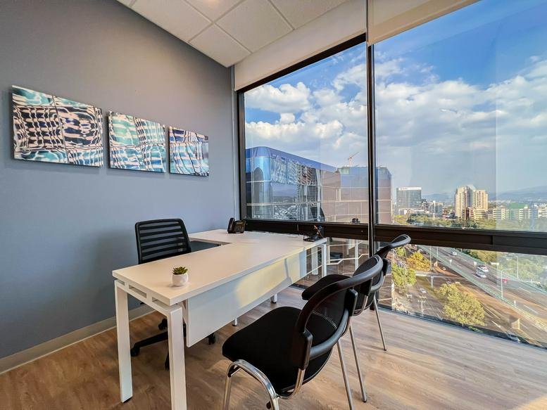 Private window office at Periferico Sur 4118 with an L-shaped desk and expansive urban views.