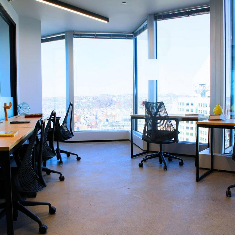 Bright corner office suite with ergonomic black chairs and expansive city views.