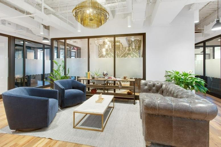 Spacious communal lounge at Rock Center, 600 Fifth Avenue, featuring plush blue armchairs and a gold chandelier.