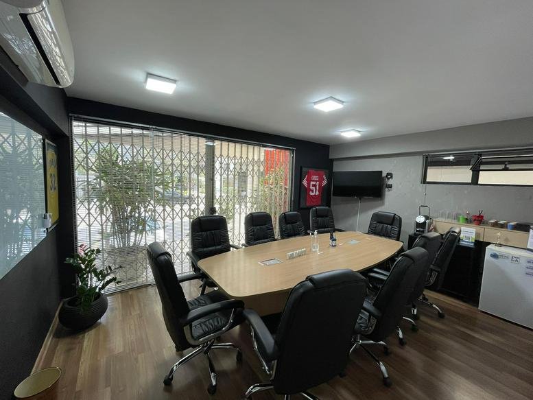 Meeting room at Rua Cônego Eugênio Leite 623 with a large oval table and black leather chairs.