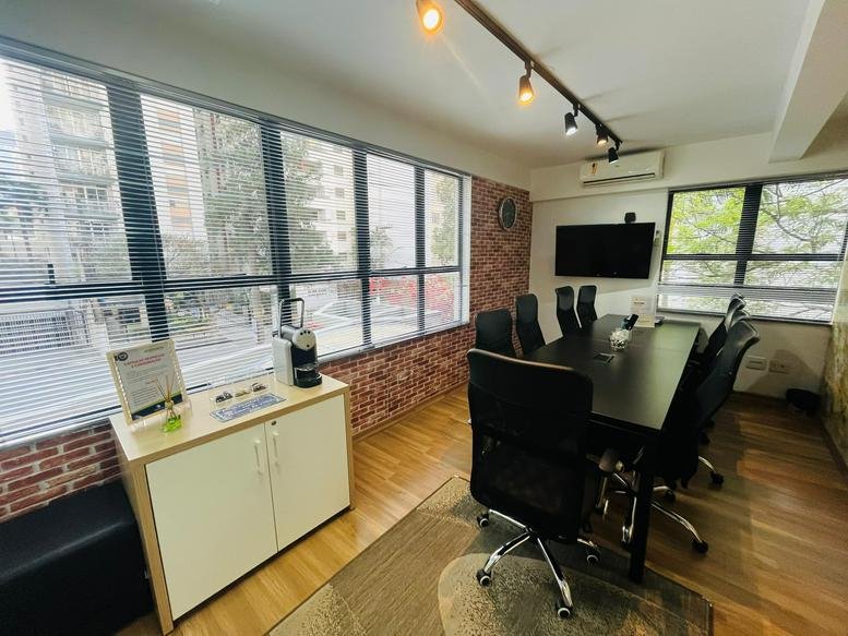 Meeting room at Rua Cônego Eugênio Leite 623 with a sleek black table and brick feature wall.