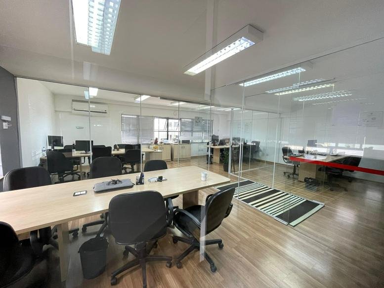 Spacious open-plan workspace at Rua Cônego Eugênio Leite 623 with glass partitions and wooden floors.