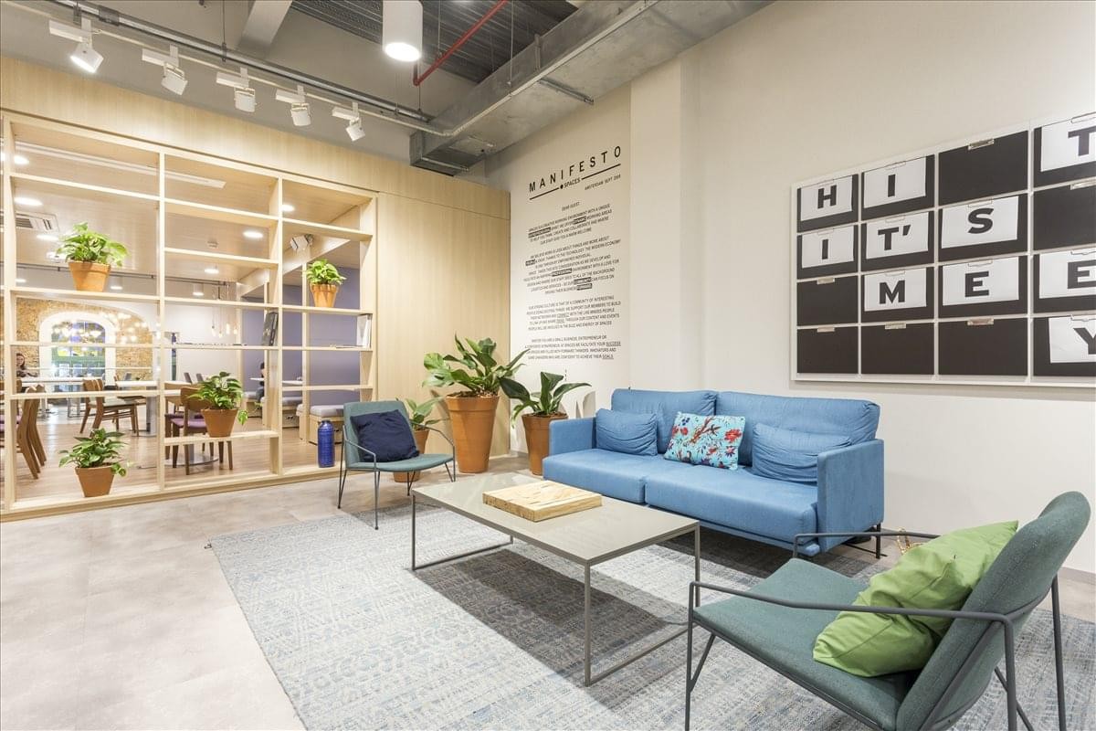Vibrant lounge area with a blue sofa, plants, and word-art wall decor.