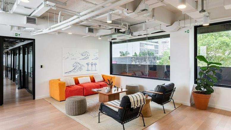 Modern lounge at Rua Oscar Freire, 585, Jardim Paulista with a bright orange sofa and large windows.