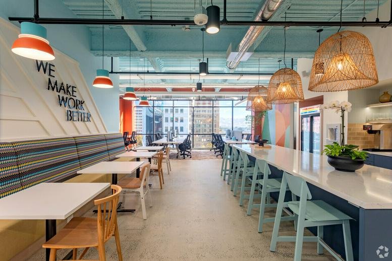 Stylish communal breakout area with a long high-top table, wicker pendant lights, and cafe seating.