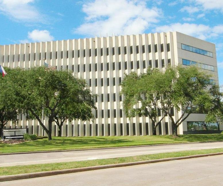 The multistory concrete and glass facade of Stafford, Houston, Texas under a bright blue sky.
