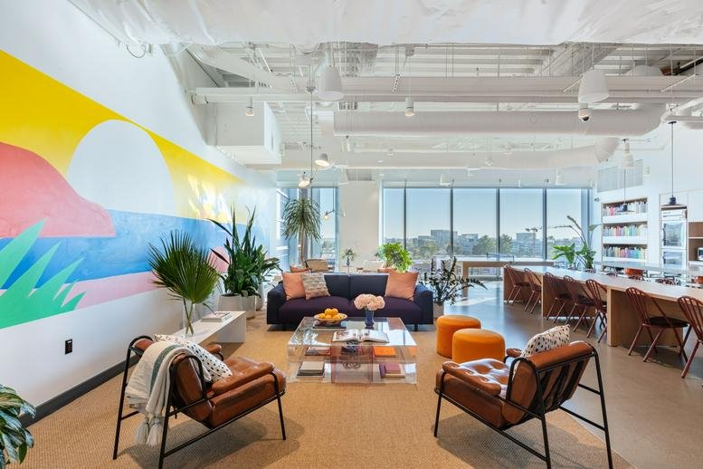 Spacious communal lounge at The Boardwalk featuring a vibrant sun-themed mural and leather armchairs.