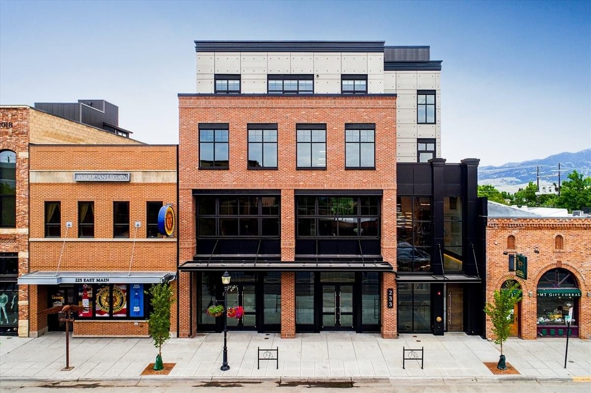 Street-level view of the brick facade of The Osborne building with large storefront windows.