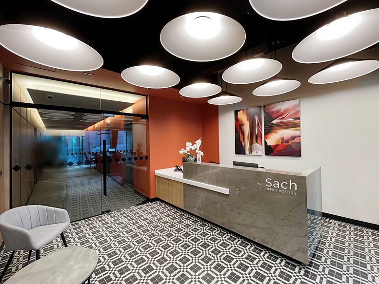 Reception area at Torre Helix featuring a stone desk, orange accent wall, and circular pendant lights.
