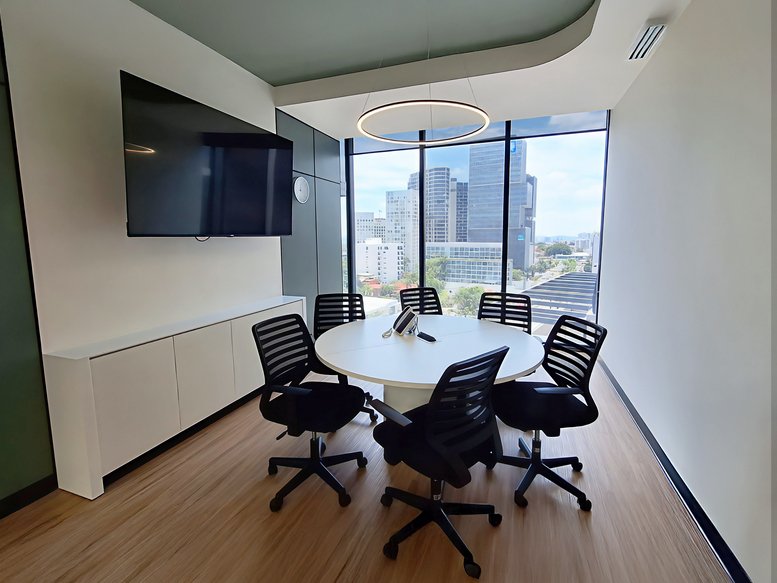 Small meeting room with a round white table, five chairs, and panoramic city views.