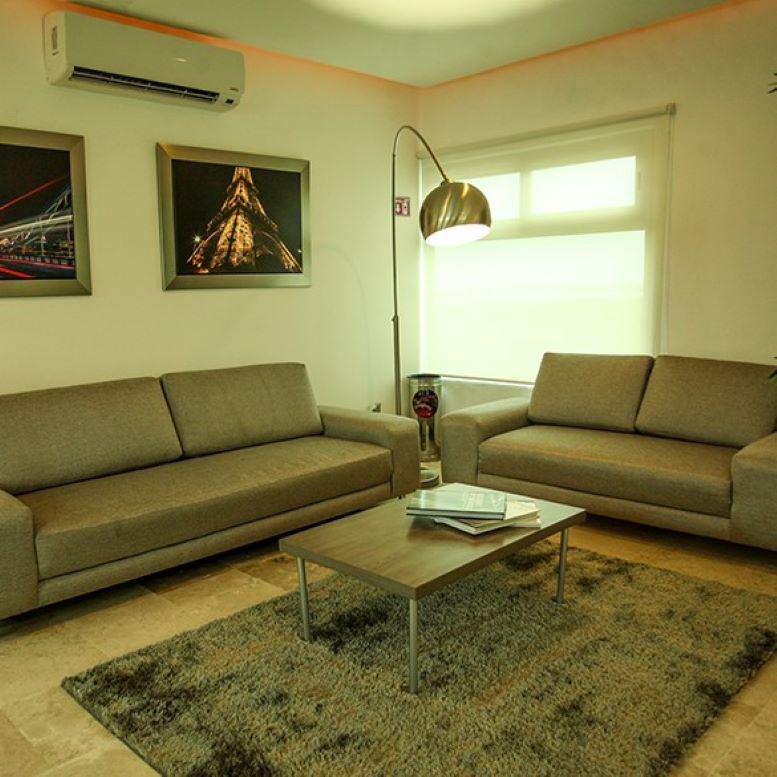 Lounge area featuring tan leather sofas, a wooden coffee table, and an arched floor lamp.