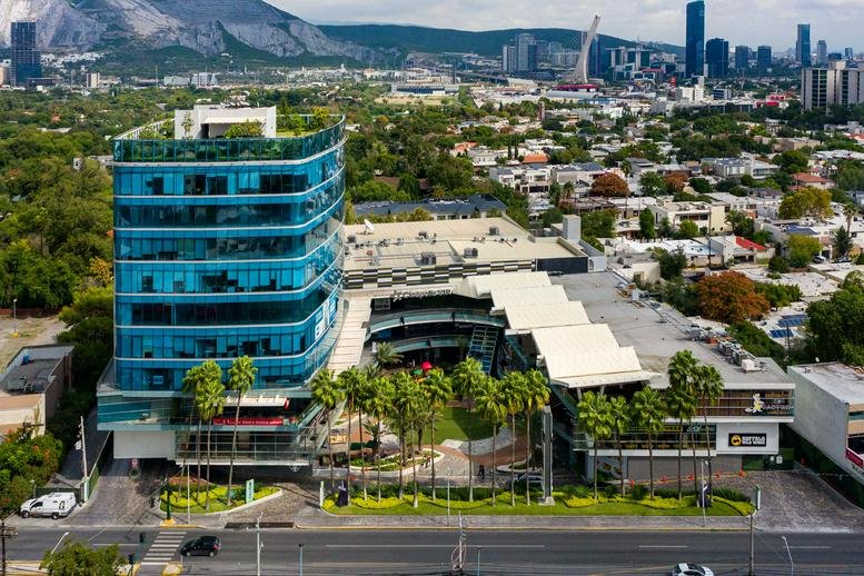 Exterior view of the glass-facade Vasconcelos No. 755 Poniente building with a green courtyard.