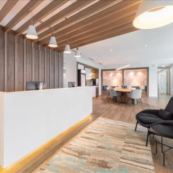 Minimalist reception area with a white desk, wooden slat wall, and pendant lighting.