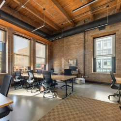 Sunlit open-plan office with exposed brick and timber ceilings.