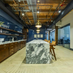 Communal kitchen with a long marble island and wood-beamed ceiling.