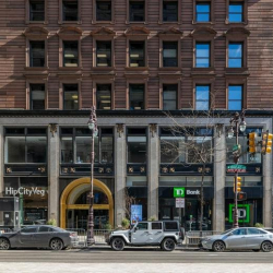Exterior view of the historic brick facade with ground-level retail and a grand arched entrance.