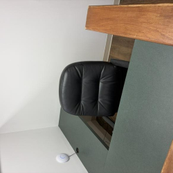 Close-up of a modern workstation featuring a black leather chair and a dark desktop.