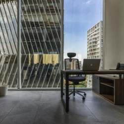 Corner workstation with a wooden desk and views of neighboring glass buildings.