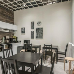 Contemporary office kitchen with white cabinets and dark wood accents.