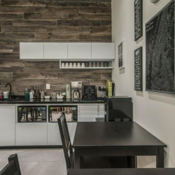 Open kitchen and breakroom area with cafe-style seating and black tables.