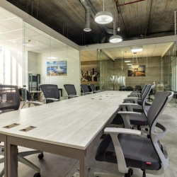 Large shared workspace with a long table and overhead industrial lighting.
