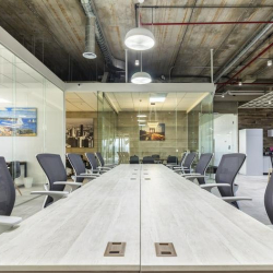 Spacious open-plan workspace with a long white table and industrial ceilings.