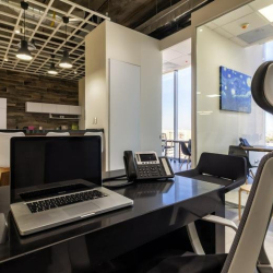 Individual workstation with a laptop and ergonomic chair in a bright office.