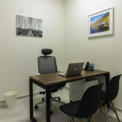 Minimalist private office with a dark wood desk and black guest chairs.