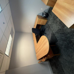 Private office featuring a curved wooden desk and grey patterned carpet.