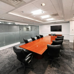 Professional boardroom with a wall-mounted screen and long wooden table.