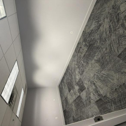 Office workspace with a wrap-around wood desk and ergonomic seating.