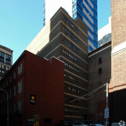 Empty interior room with neutral grey carpet tiles and white walls.