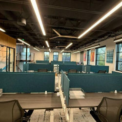Open-plan workspace with teal privacy partitions and rows of modern desks.