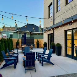 Outdoor patio area with blue Adirondack chairs and overhead string lights.