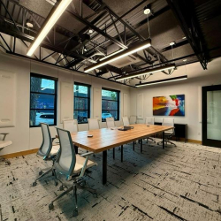Professional conference room with a long wood table and white mesh chairs.