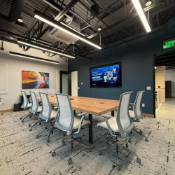 Modern meeting space equipped with a wall-mounted screen and ergonomic seating.