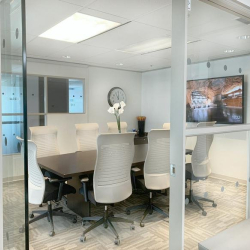Glass-enclosed meeting room at Chadwick Court with white chairs and a dark conference table.