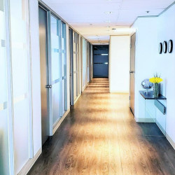 Brightly lit corridor with glass office doors and wood floors.
