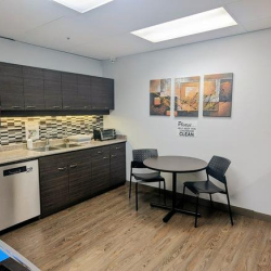 Modern kitchenette with dark cabinetry and a small dining area.