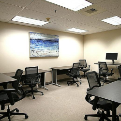 Open-plan workspace with multiple black desks and ergonomic mesh chairs.
