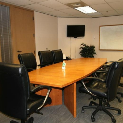 Modern conference room equipped with a large media screen and polished wood table.