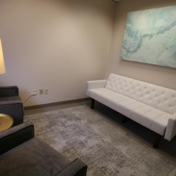 Contemporary lounge area with a tufted white sofa and abstract blue wall art.